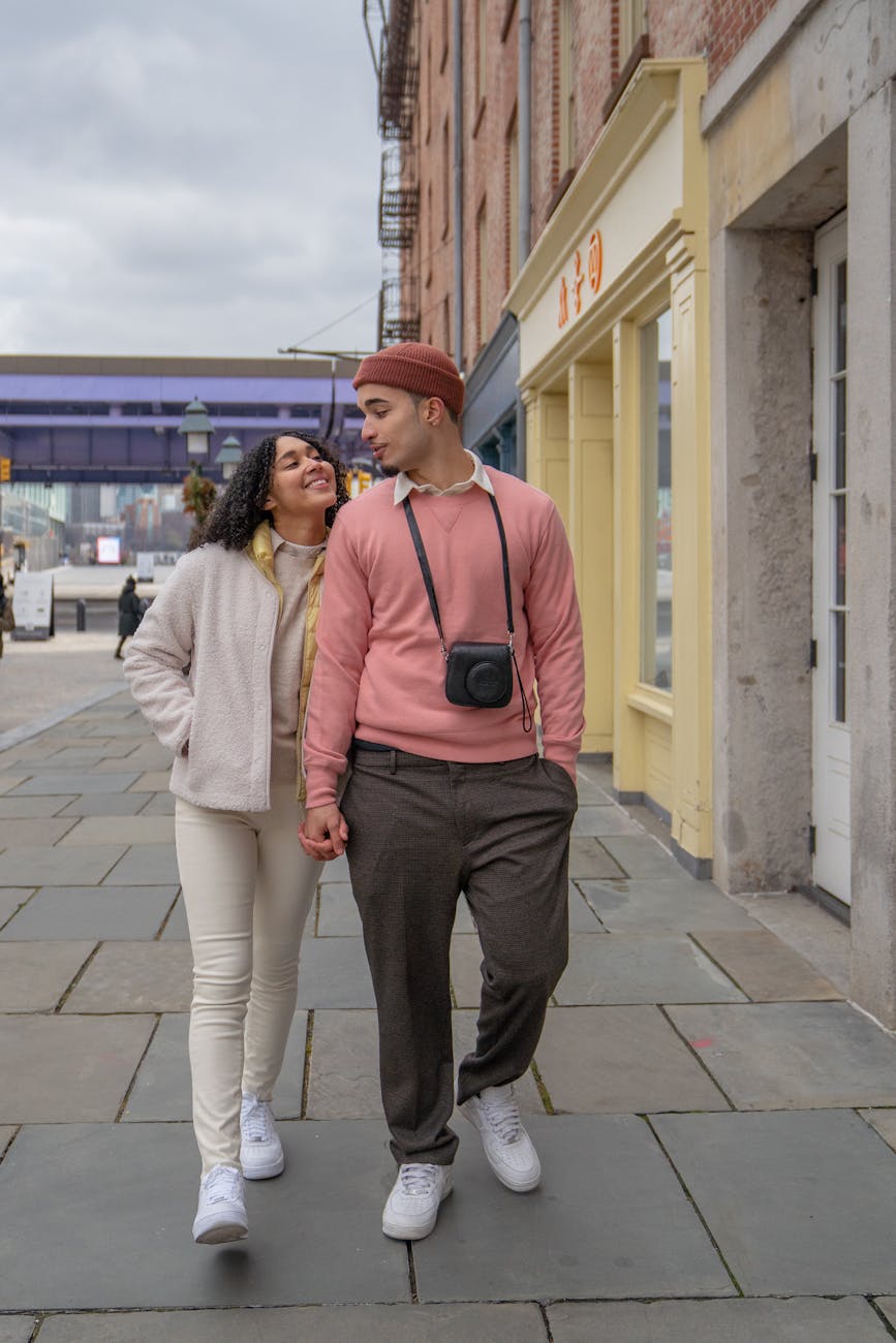 cheerful hispanic couple holding hands and walking on street